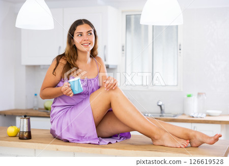 Portrait of sexy girl with cup of coffee on kitchen table at home Portrait of sexy girl with cup of coffee on kitchen table at home 126619528