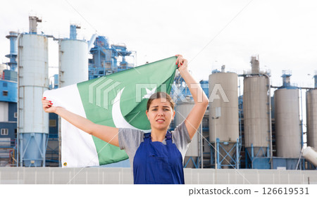 upset woman in blue worker s overalls stands near country factory and holds Pakistani flag upset woman in blue worker s overalls stands near country factory and holds Pakistani flag 126619531