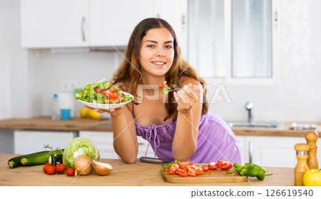 Portrait of housewife eating vegetable salad at table at home Portrait of housewife eating vegetable salad at table at home 126619540