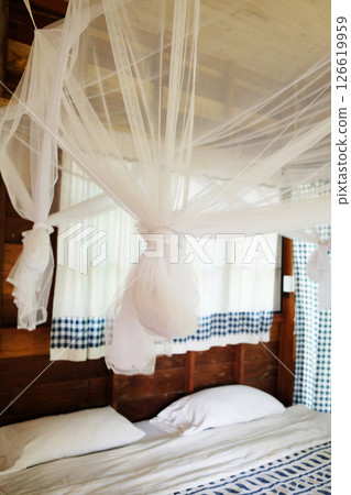 Close up Mosquito netting hanging around bed frame in vintage bedroom of Tradition wooden homestay in Thailand 126619959