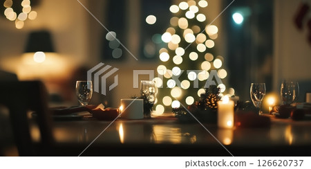 Warmly lit festive dinner table with candles, glassware, and bokeh Christmas tree lights in the background. Ideal for holiday ads, celebration visuals, cozy interiors or seasonal lifestyle content. 126620737