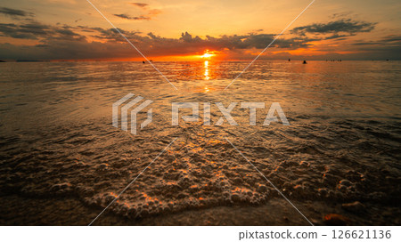 Summer Sunset Over the Water,sun setting low over the ocean water on a summer evening Summer Sunset Over the Water,sun setting low over the ocean water on a summer evening 126621136