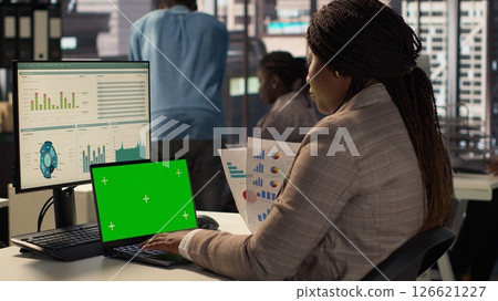 Corporate employee focused on strategic planning next to green screen on pc, accomplishing business objectives. Female consultant engaged in budget analysis and performance metrics. Camera A. Corporate employee focused on strategic planning next to green screen on pc, accomplishing business objectives. Female consultant engaged in budget analysis and performance metrics. Camera A. 126621227