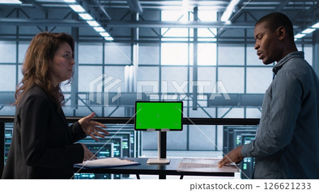 Data center team using mockup green screen tablet, reviewing paperwork files, and security protocols. Server room admins next to chroma key device analyzing critical system reports, camera A Data center team using mockup green screen tablet, reviewing paperwork files, and security protocols. Server room admins next to chroma key device analyzing critical system reports, camera A 126621233