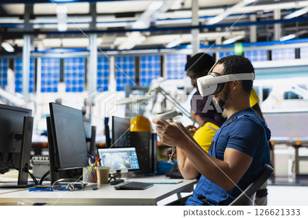Photovoltaics facility specialist using VR tech to build models of alternative energy generators. Solar panels factory male employee building safe solar cells using virtual reality gear. Photovoltaics facility specialist using VR tech to build models of alternative energy generators. Solar panels factory male employee building safe solar cells using virtual reality gear. 126621333