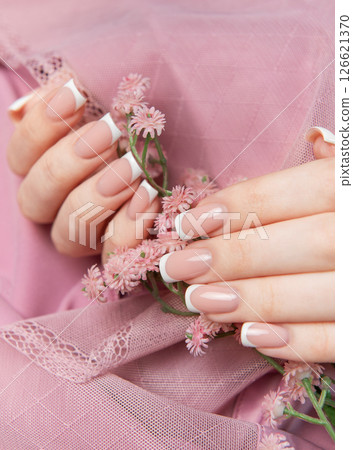 Woman showing french manicure holding pink flowers on pink background 126621370