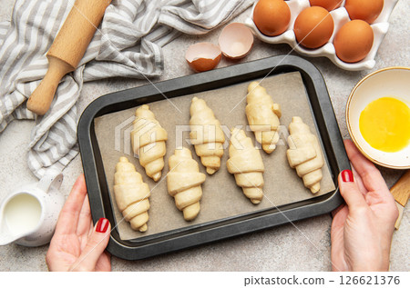 Baker holding baking tray with freshly made croissants, ready to bake Baker holding baking tray with freshly made croissants, ready to bake 126621376
