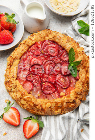 Delicious homemade strawberry galette decorated with almond petals and fresh mint 126621395
