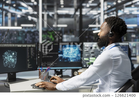 Employee talking in headset mic with technicians setting up data center equipment needed to run artificial intelligence. Server room worker in remote call with engineers installing AI tools Employee talking in headset mic with technicians setting up data center equipment needed to run artificial intelligence. Server room worker in remote call with engineers installing AI tools 126621400