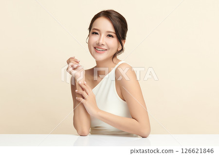 A beautiful young Asian woman with clean, fresh skin against a beige background. Skincare, facial treatment, cosmetology, beauty, and spa. An elegant portrait of an Asian woman. 126621846