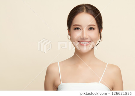 A beautiful young Asian woman with clean, fresh skin against a beige background. Skincare, facial treatment, cosmetology, beauty, and spa. An elegant portrait of an Asian woman. 126621855