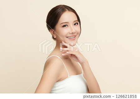 A beautiful young Asian woman with clean, fresh skin against a beige background. Skincare, facial treatment, cosmetology, beauty, and spa. An elegant portrait of an Asian woman. 126621858