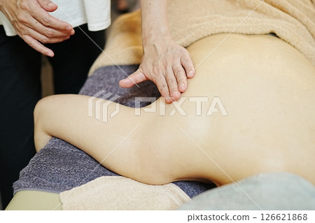 Therapist gently massaging the shoulder blade area 126621868