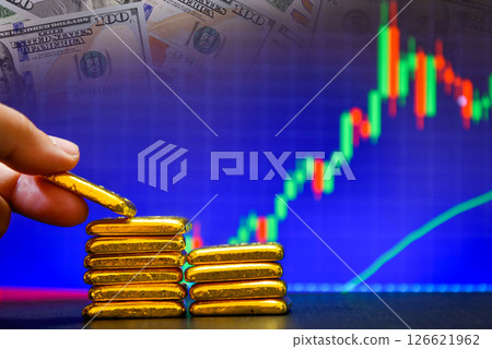 Close up photo hand holding a gold bars the candlestick chart and us dollar background , Fluctuations in gold prices concept 126621962