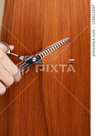 Hairdresser cuts long red hair with scissors Hairdresser cuts long red hair with scissors 126622097