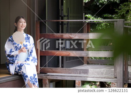 A woman in a yukata relaxing on the veranda of an old house, looking up 126622131