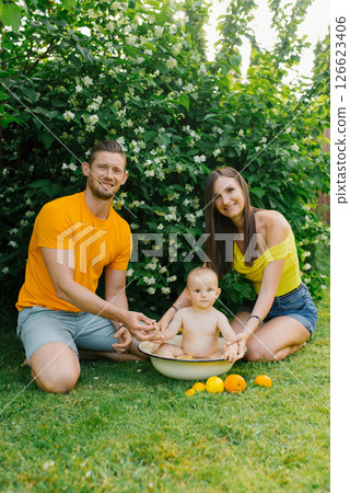 Family with Baby Sitting in Tub Outdoors with Oranges 126623406