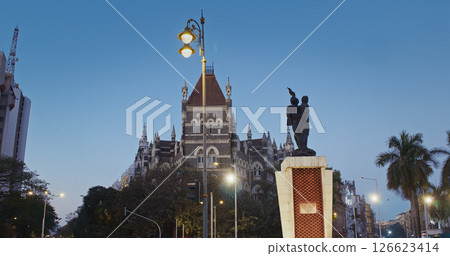 Mumbai, India. People Walk Throw Hutatma Chowk Or Martyrs Square. Square Hosts Flora Fountain. Statue Of Martyr With Flame Stands Next To Flora Fountain. Dusk In City. Busy Traffic In City Street 126623414