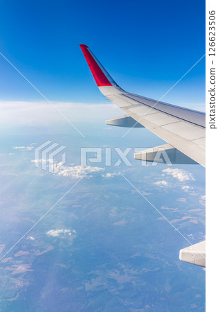 View from the airplane window at a beautiful cloudy sky and the airplane wing 126623506