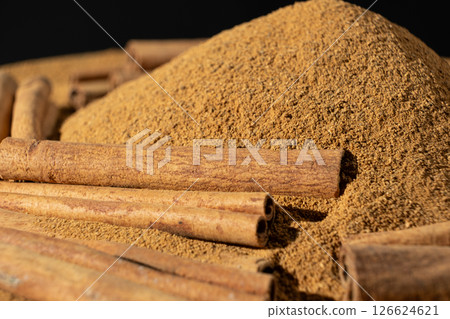 Close-Up of Brown Ground Spice and Cinnamon Sticks. Natural Food Scene. Close-Up of Brown Ground Spice and Cinnamon Sticks. Natural Food Scene. 126624621