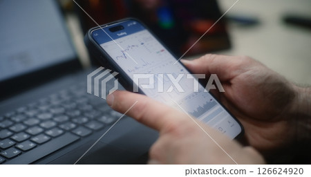 Man Checking Exchange Market Charts on Smartphone and Laptop. Close Up Man Checking Exchange Market Charts on Smartphone and Laptop. Close Up 126624920