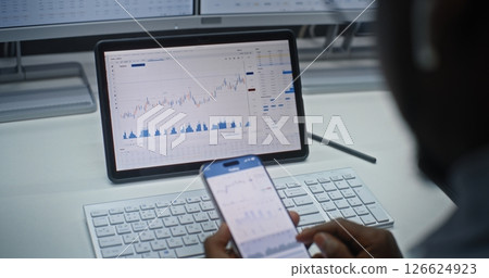 Stock Exchange Trader Analyzing Exchange Market Charts on Smartphone and Tablet Computer Stock Exchange Trader Analyzing Exchange Market Charts on Smartphone and Tablet Computer 126624923
