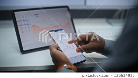 Stock Exchange Broker Analyzing Exchange Market Charts on Smartphone and Digital Tablet 126624935