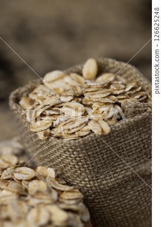 a bag with oatmeal flakes for porridge, scattered dry cereal flakes from oats, flattened, steamed and dried, close up 126625248