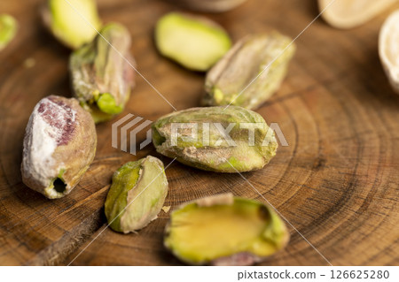 pistachios without shells, cut into pieces on a board, closeup pistachios without shells, cut into pieces on a board, closeup 126625280