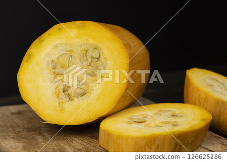 cut yellow pumpkin or zucchini, slicing ripe zucchini on a black table cut yellow pumpkin or zucchini, slicing ripe zucchini on a black table 126625286