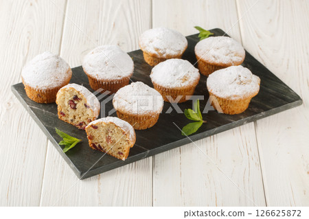 Stollen muffins fruit bread with dried fruit and marzipan coated with powdered icing sugar closeup on the board. Horizontal Stollen muffins fruit bread with dried fruit and marzipan coated with powdered icing sugar closeup on the board. Horizontal 126625872