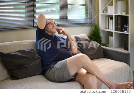 Senior man talking on the phone at home with a worried expression Senior man talking on the phone at home with a worried expression 126626153