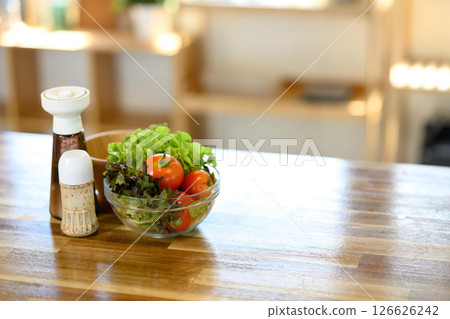 Fresh salad ingredients and seasoning bottles on a wooden kitchen counter in natural light 126626242