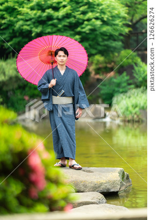 A man wearing a kimono and holding a snake-eye umbrella A man wearing a kimono and holding a snake-eye umbrella 126626274