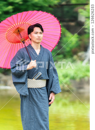 A man wearing a kimono and holding a snake-eye umbrella A man wearing a kimono and holding a snake-eye umbrella 126626283