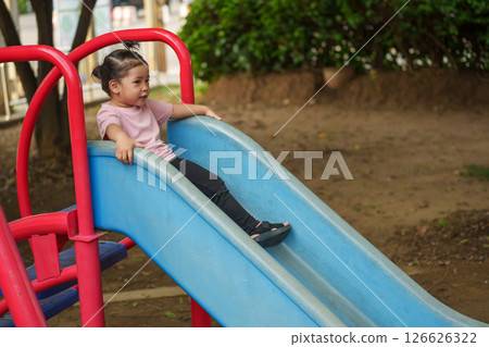 happy toddler baby girl sliding and playing at playground happy toddler baby girl sliding and playing at playground 126626322