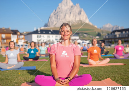 group of women practicing yoga in a lotus position on yoga mats outdoors,a majestic mountain in the background.peacefulness,connection with nature,suitable for yoga,wellness,travel themes. 126627163