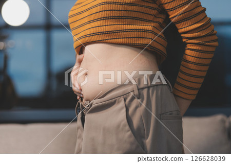 Cropped shot of woman touching and squeezing her fat belly. 126628039