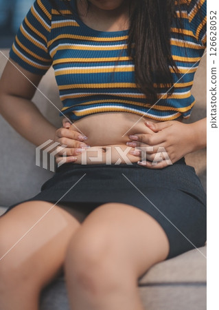 Cropped shot of woman touching and squeezing her fat belly. 126628052
