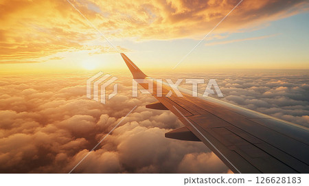 Beautiful sunset view from airplane wing over soft clouds during flight at dusk Beautiful sunset view from airplane wing over soft clouds during flight at dusk 126628183
