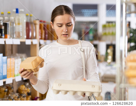 Young woman choosing eggs in grocery store 126628620