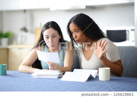 Surprised interracial women checking bank statement Surprised interracial women checking bank statement 126628661