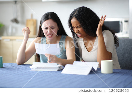 Angry women checking bank statement at home Angry women checking bank statement at home 126628663
