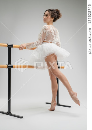Ballet dancer poses gracefully in studio with light and shadows at play 126628746