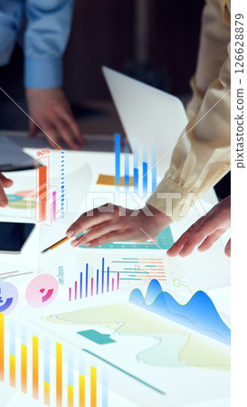 Conceptual collage. Finger pointing at transparent chart with linear data and bar performance stats, surrounded by glowing financial icons. Concept of financial 126628879
