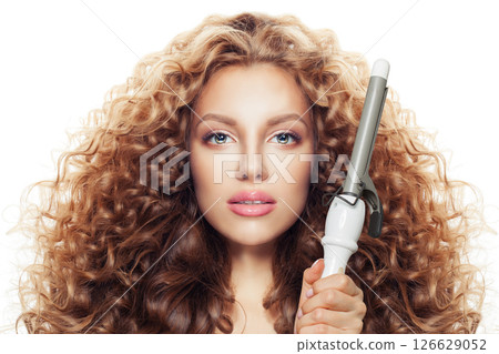 Gorgeous young model woman with long curly wavy hairstyle showing hot curling tongs iron  126629052
