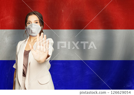 Confident woman in medical mask showing stop gesture open palm hand against flag of France  126629054