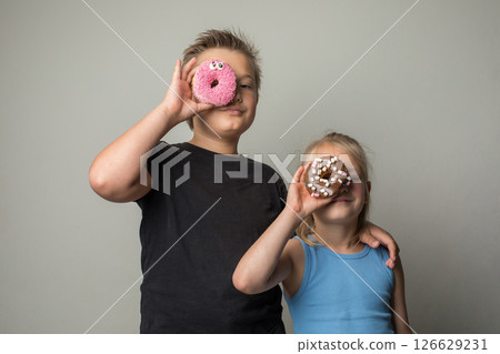 Cute children holding chocolate glazed donut indoor. Happy kids with sweet food portrait Cute children holding chocolate glazed donut indoor. Happy kids with sweet food portrait 126629231