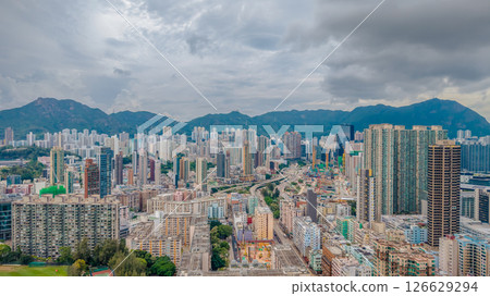View of a Dense Urban Landscape Against Mountain Skyline and Cloudy Sky View of a Dense Urban Landscape Against Mountain Skyline and Cloudy Sky 126629294