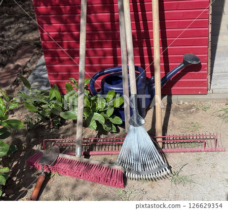 A variety of garden tools positioned on artificial grass for outdoor gardening. Several garden tools, including a rake, shovel, and pruners, are arranged on a patch of artificial grass 126629354